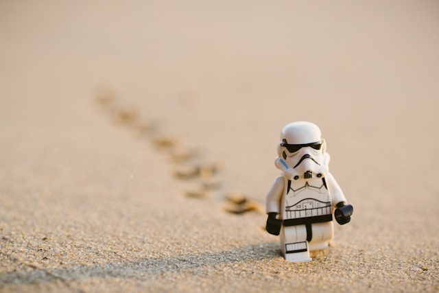 A mini robot toy leaves footprints on the sand.