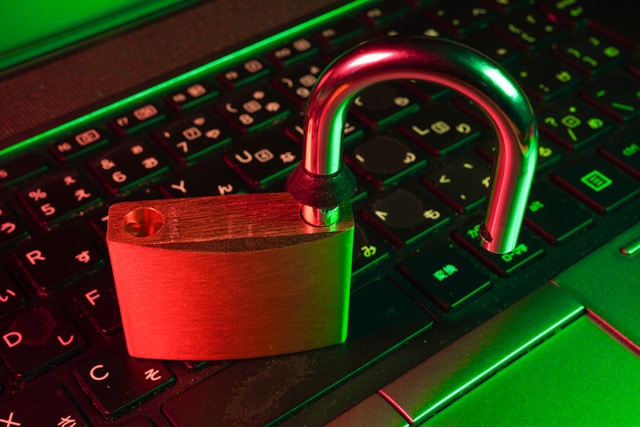 An unlocked padlock sits on top of a laptop keyboard. 