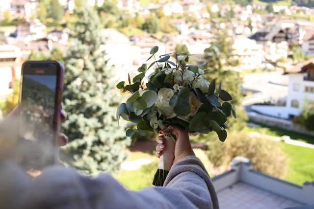 Uma mulher usa seu telefone para fazer um vídeo de seu buquê de flores. 