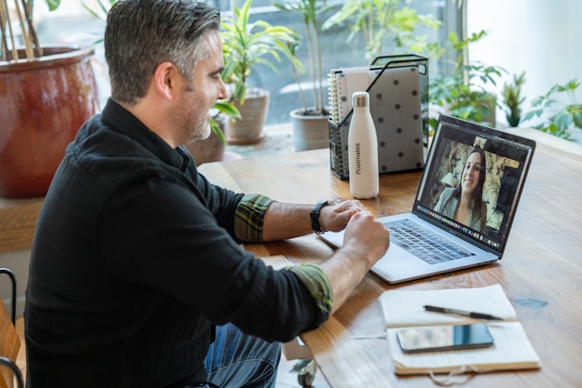 Um homem senta-se em frente ao seu laptop durante uma chamada de vídeo. 