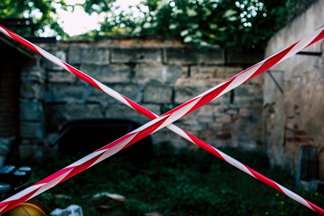 Criss-crossed red and white tapes block off a path. 
