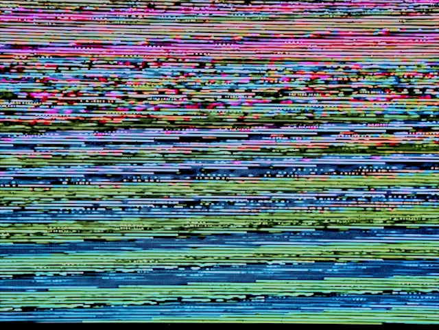 A digital screen displays a glitching image. 
