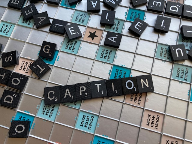 Black and white Scrabble tiles spell the word “CAPTION.”