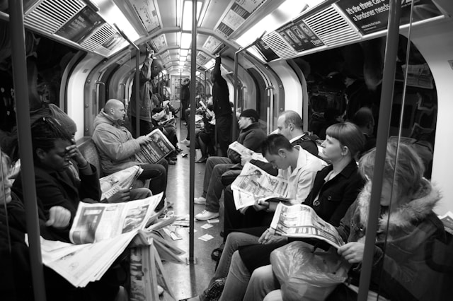 People on a train are reading newspapers. 
