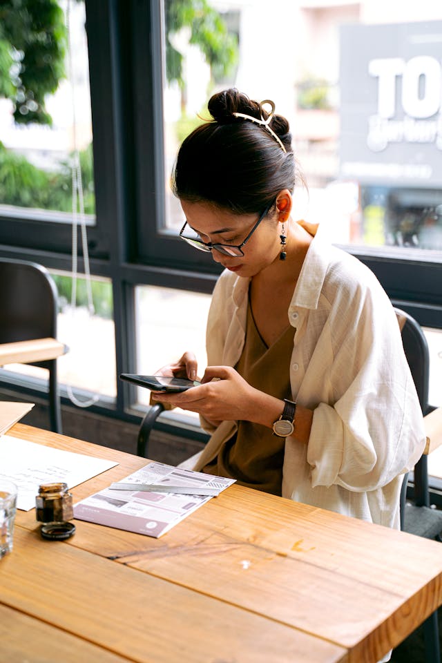 A woman uses her cell phone at a table.
