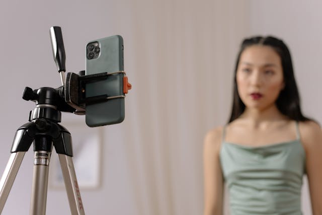 A woman in a green dress stares at a mounted cell phone.