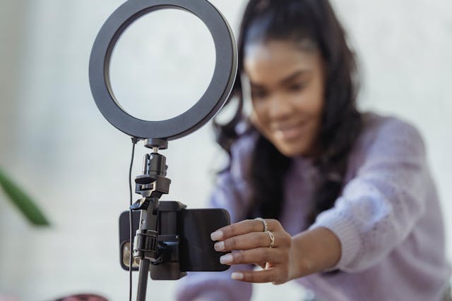 A person sets up a phone on a ring light stand to record a video.
