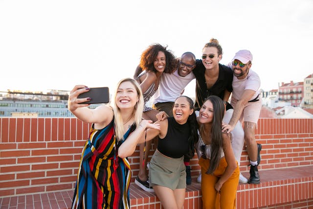 Um grupo de homens e mulheres tirando uma selfie.