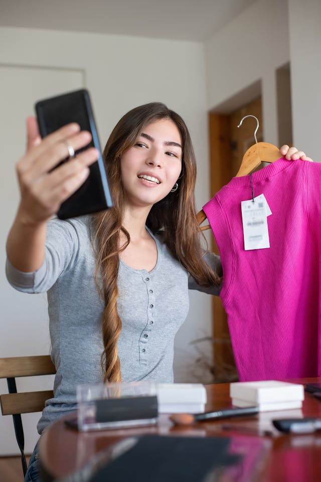 A woman shows off a bright pink shirt to her followers.