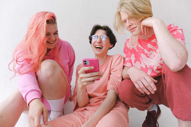 Two young ladies and a man in pink clothes smiling.