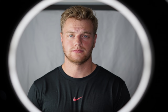 A man stands in front of a ring light for a TikTok video. 
