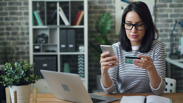 A woman enters her credit card information into her phone. 