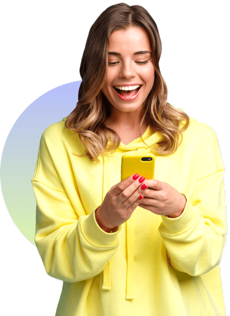 A woman wears a big smile as she looks at her phone. 
