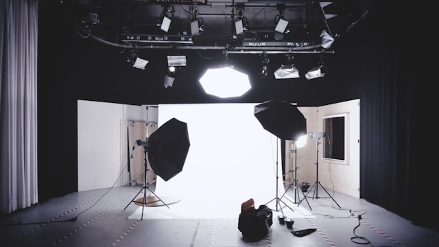 A space is set up with lights and a white background for a video shoot. 
