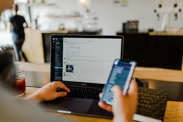 A person checks their online store’s performance on a computer while using a phone.
