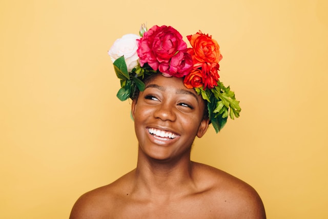 A female influencer smiles while wearing a colorful flower crown. 
