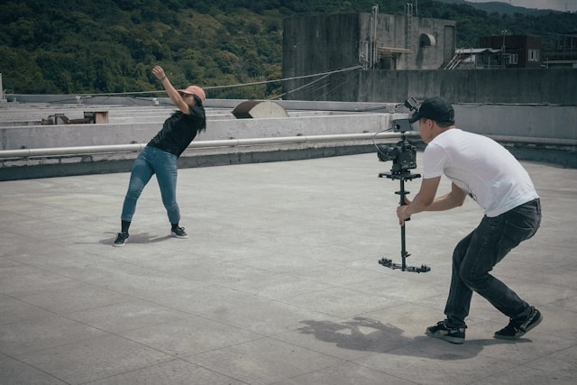 A man takes a video of a woman performing a dance routine on a rooftop.
