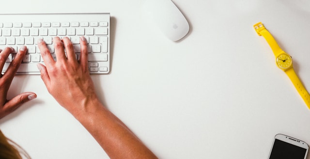 A person types on a white keyboard. 
