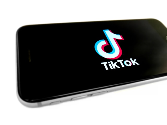A phone screen displays the TikTok logo. 