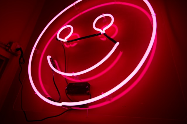 A red neon sign in the shape of a smiley face. 
