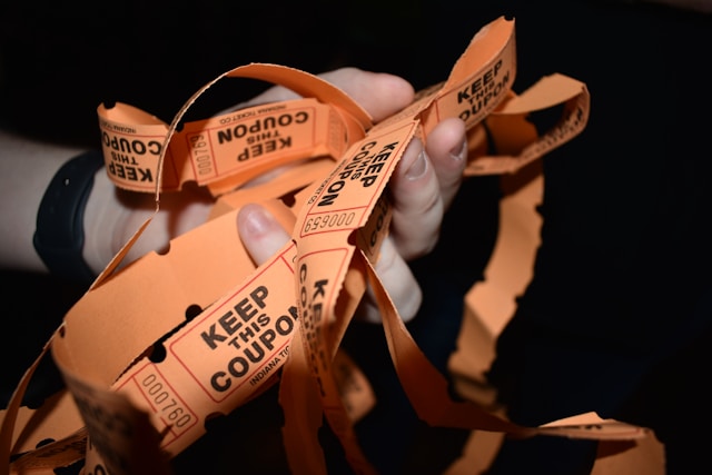 A person holds lots of brown coupon strips. 
