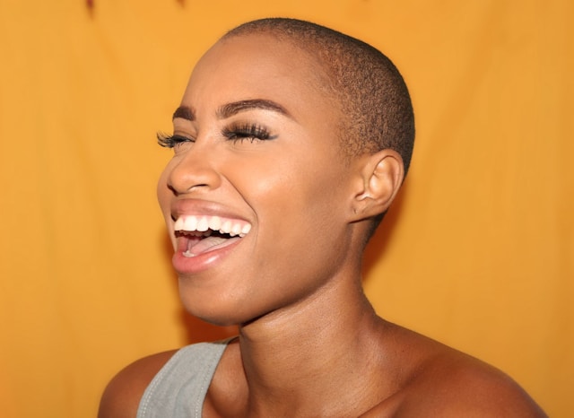 A beauty influencer models makeup products and laughs for the camera.
