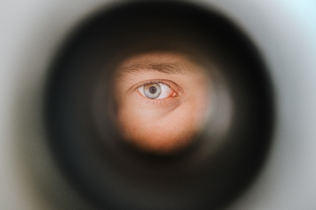 A person’s eye peeks through a camera lens. 
