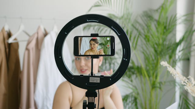 A phone in a ring light records a woman.