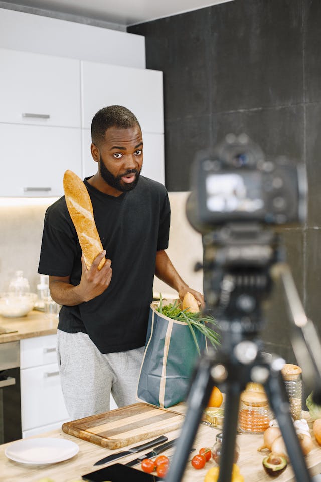 A man shows a baguette to a recording camera.

