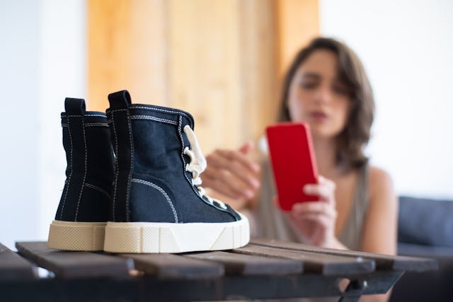 A woman photographs a pair of shoes.

