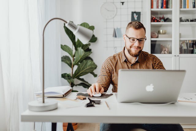 A man sits around his laptop, scrolling.
