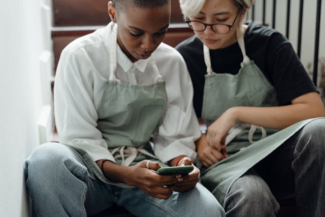 Two women look at a phone.
