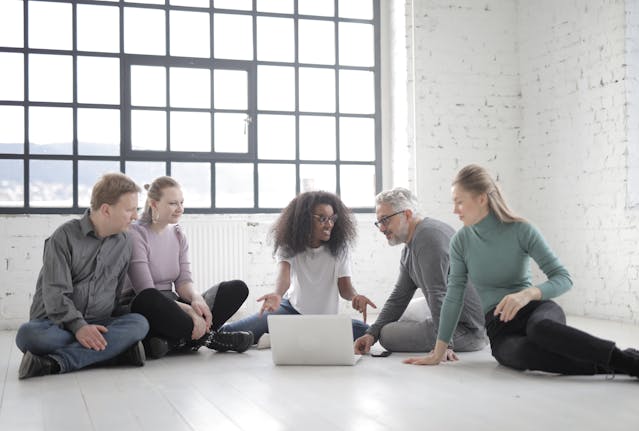 Un groupe de personnes se rassemble autour d’un ordinateur portable.