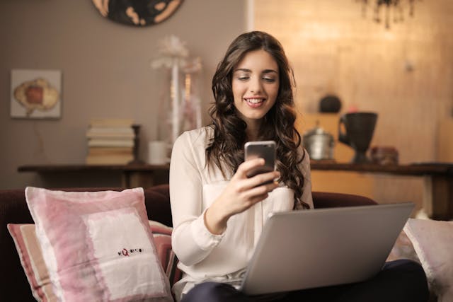 Une femme sourit à son téléphone portable.