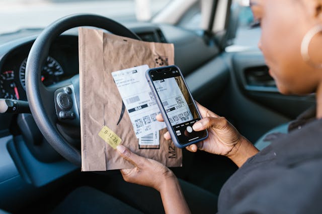 A woman takes a picture of a parcel.
