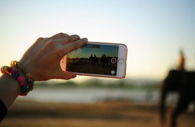 A person records a video using landscape mode.
