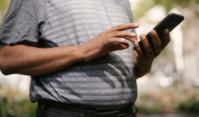 A man outside taps on his cell phone.