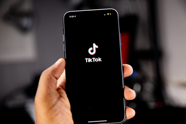 一个人拿着一部显示 TikTok 徽标的黑色 iPhone。