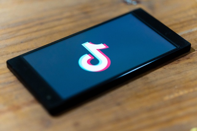 A mobile phone displays the TikTok logo/music note.
