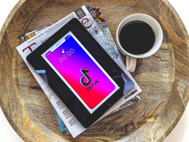 A tablet on a stack of books displays the TikTok logo beside a cup of coffee.