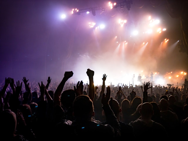 A big and energetic crowd stands in front of a band on a stage. 
