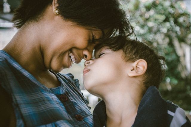 A mother smiles as she and her daughter touch noses. 
