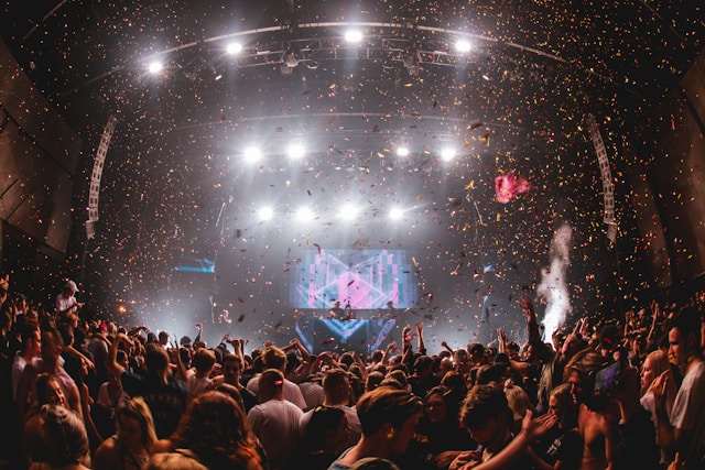 Confetti falls from above and over a throng of people at a music festival. 
