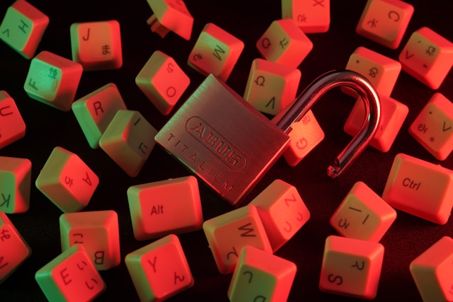 An unlocked padlock sits among dislodged pieces of computer keyboard keys. 
