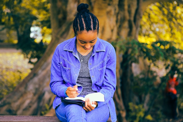 A young woman writes a list of potential TikTok usernames in her notebook. 
