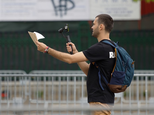 A person records a video on a street using a selfie stick.
