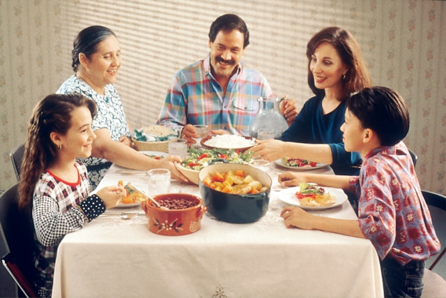 A happy family sits around the dinner table. 
