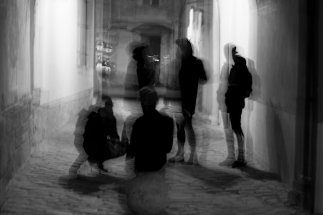 A blurry image of a group of people in an empty hallway. 

