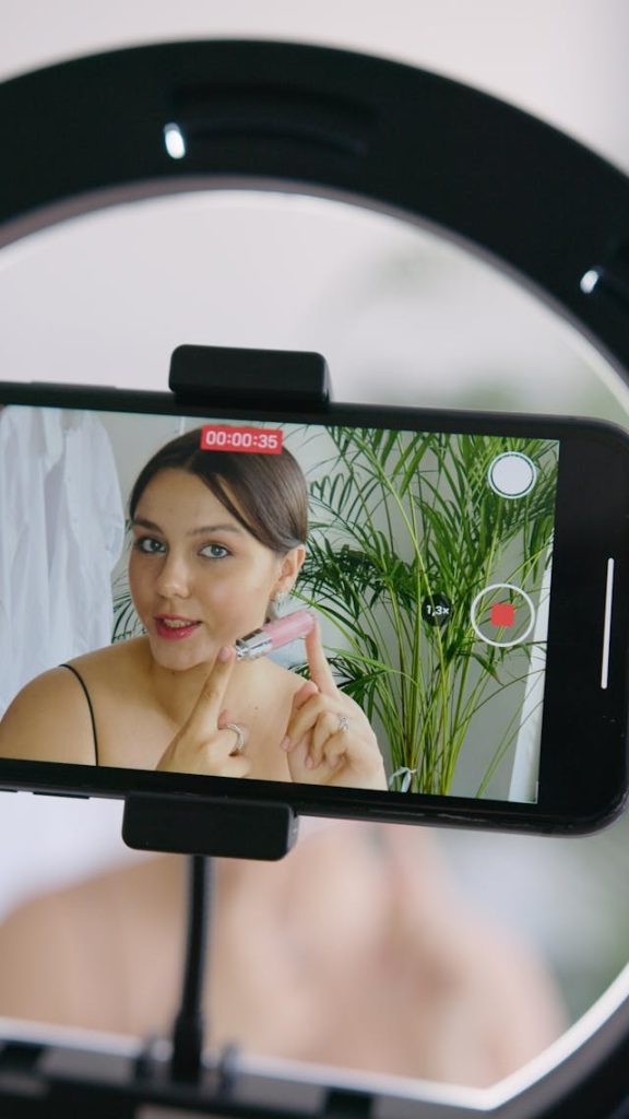 A camera records a woman showing off a lip gloss.
