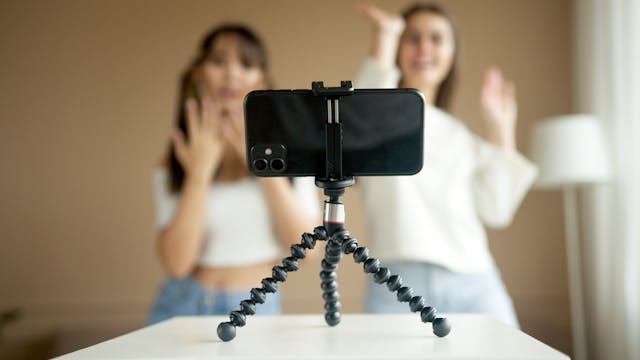 A mounted cell phone records two girls dancing.
